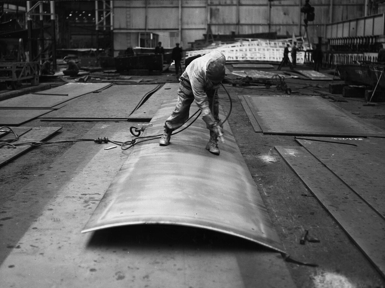Worker spray-applying protective coating to steel — representative photo, replace with VELARIA product photography